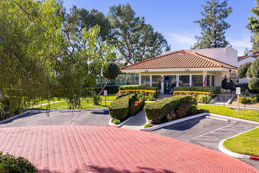 Clubhouse exterior with tile roof and landscaped grounds at Woodbend Apartments, Alta Loma, CA 91701