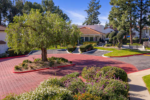 Brick paved driveway with tree lined entrance at Woodbend Apartments, Alta Loma, CA