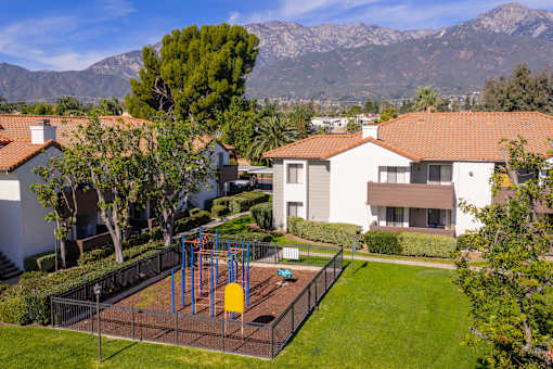 Playground area with mountain views and residential buildings at Woodbend Apartments, Alta Loma