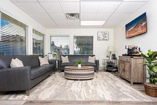 Modern waiting room with gray sofas and coffee table at Woodbend Apartments, California