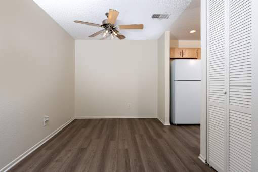 Empty living room with ceiling fan and kitchen at Woodbend Apartments, Alta Loma, CA 91701