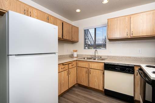 Kitchen with wood cabinets and white appliances at Woodbend Apartments, Alta Loma, CA