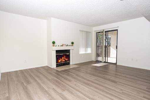 Spacious living room with fireplace and balcony access at Woodbend Apartments, Alta Loma, California