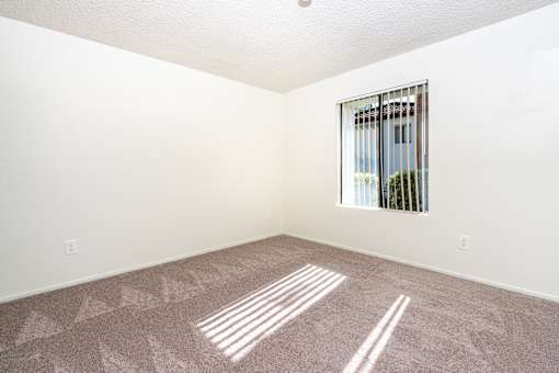 Empty carpeted bedroom with window blinds at Woodbend Apartments, Alta Loma