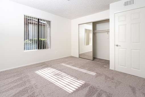 Spacious bedroom with walk-in closet and carpet at Woodbend Apartments, California