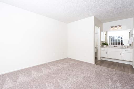 Spacious bedroom with carpet and ensuite bathroom at Woodbend Apartments, Alta Loma, CA 91701