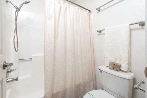 Bathroom with tub shower combo and white fixtures at Woodbend Apartments, Alta Loma, CA