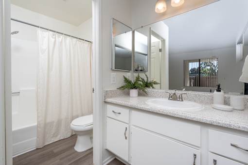 Bathroom with white vanity and shower tub combo at Woodbend Apartments, Alta Loma, 91701