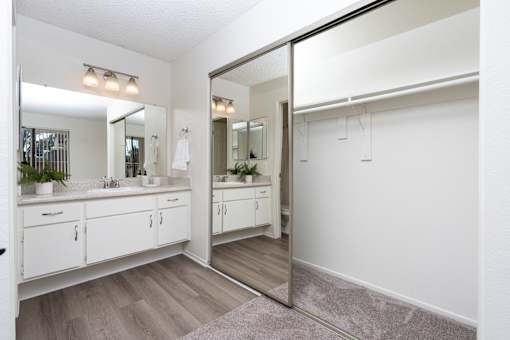Bathroom vanity with large mirrored closet doors at Woodbend Apartments, Alta Loma, California