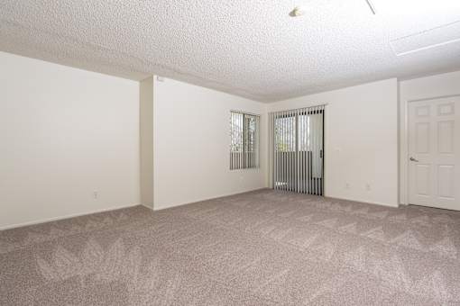 Empty carpeted living room with vertical blinds at Woodbend Apartments, California