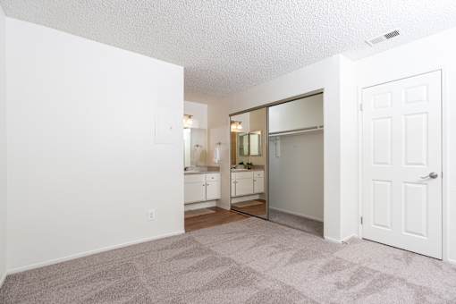 Bedroom with mirrored closet and attached bathroom at Woodbend Apartments, Alta Loma, California