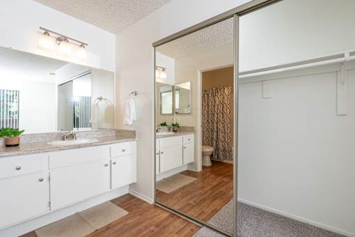 Master bathroom with dual vanities and mirrored closet at Woodbend Apartments, Alta Loma