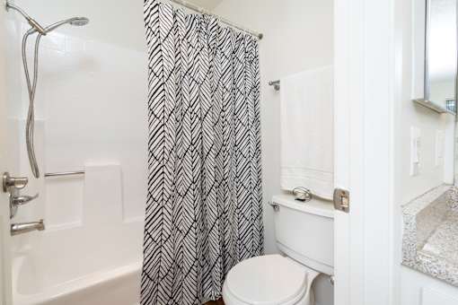 Bathroom with patterned shower curtain and tub at Woodbend Apartments, California, 91701