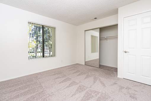 Bedroom with sliding closet doors and window at Woodbend Apartments, Alta Loma, CA 91701