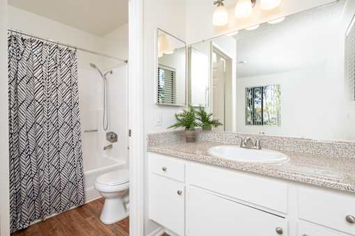 Bathroom with granite vanity and mirror medicine cabinets at Woodbend Apartments, Alta Loma, CA