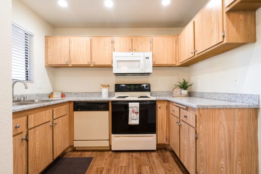 Kitchen with Wooden Cabinets and Granite-Style Countertops at Woodbend, Alta Loma
