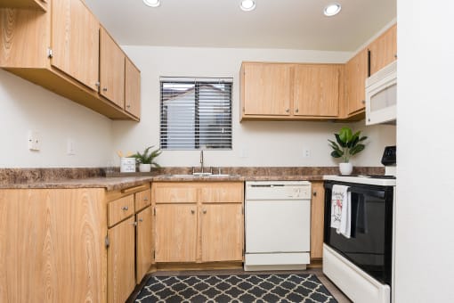 Kitchen with appliances and window at Woodbend, Alta Loma, CA, 91701