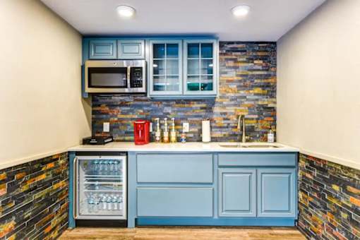 A kitchen with a blue cabinet and a stone wall.
