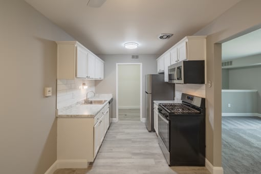 an empty kitchen with white cabinets and black appliances