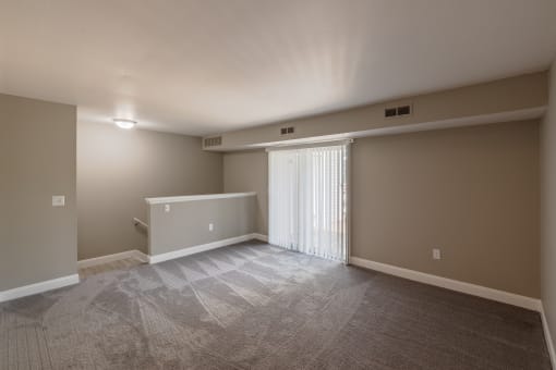an empty living room with a sliding glass door and gray walls