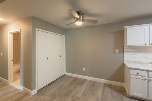 an empty living room with a ceiling fan and a kitchen