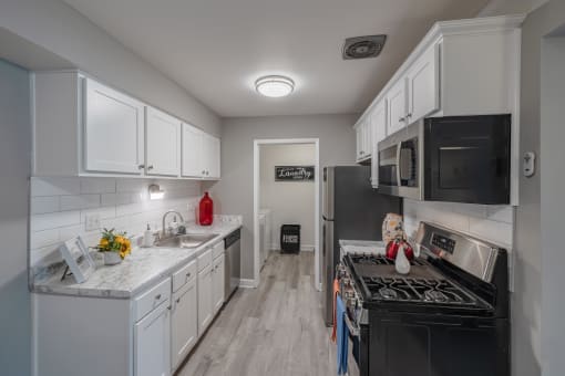 a kitchen with white cabinets and black appliances and a stove