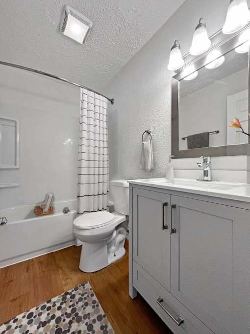 A white toilet sits in a bathroom next to a bathtub.