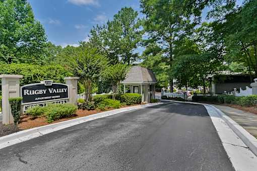 A sign that says "Rugby Valley Apartment Homes" is in front of a road.