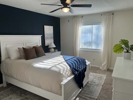 A bedroom with a bed, nightstand, and window.