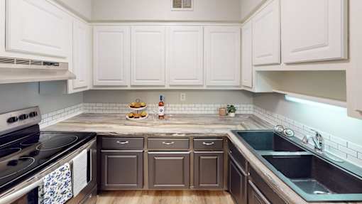 A kitchen with white cabinets and a stove top oven.