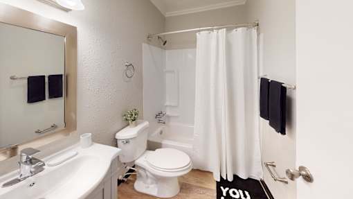 A white bathroom with a toilet, sink, and shower.
