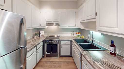 A kitchen with white cabinets and a stainless steel refrigerator.