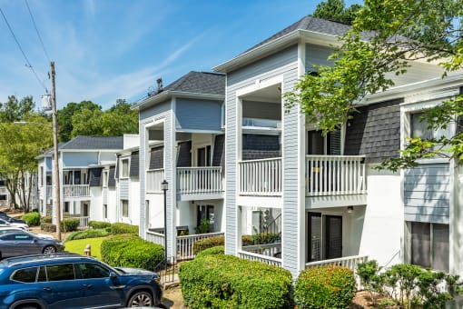 a row of white houses with cars parked in front of them
