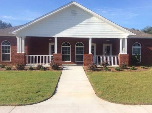 A white building with a red brick facade and a white porch.