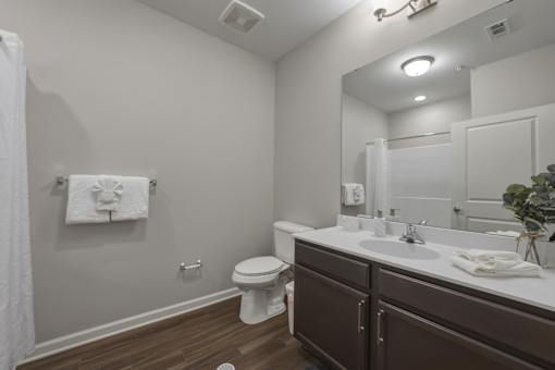 A white toilet sits in a bathroom with brown cabinets.