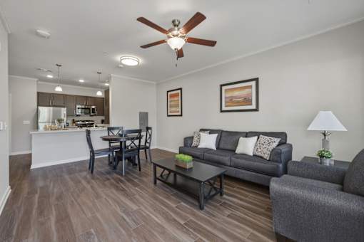 A living room with a grey couch, a black coffee table, and a ceiling fan.