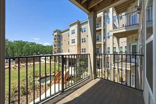 A balcony with a black railing and a view of a building and trees.
