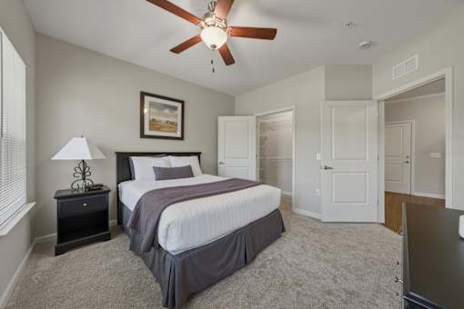 A bedroom with a bed, dresser, and ceiling fan.