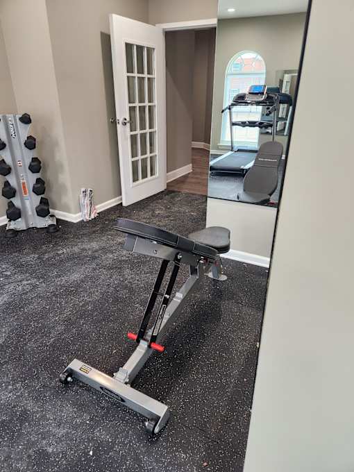 A black and silver weight bench in a room with a mirror.