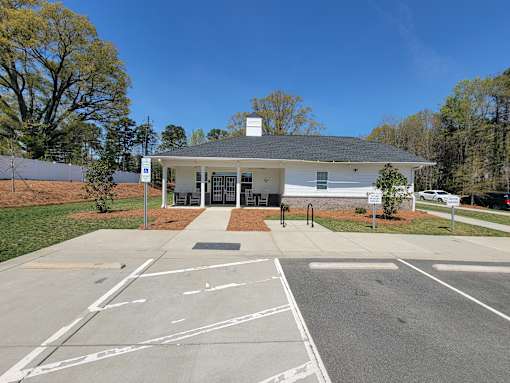 A white building with a black roof is surrounded by a parking lot.