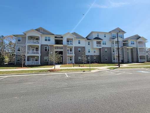 A large apartment complex with multiple buildings and a parking lot in front.