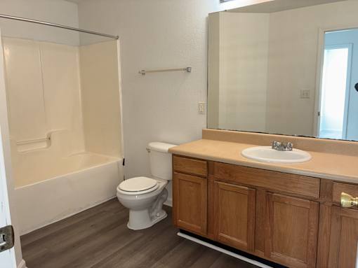 A white toilet sits in a bathroom next to a sink and a bathtub.