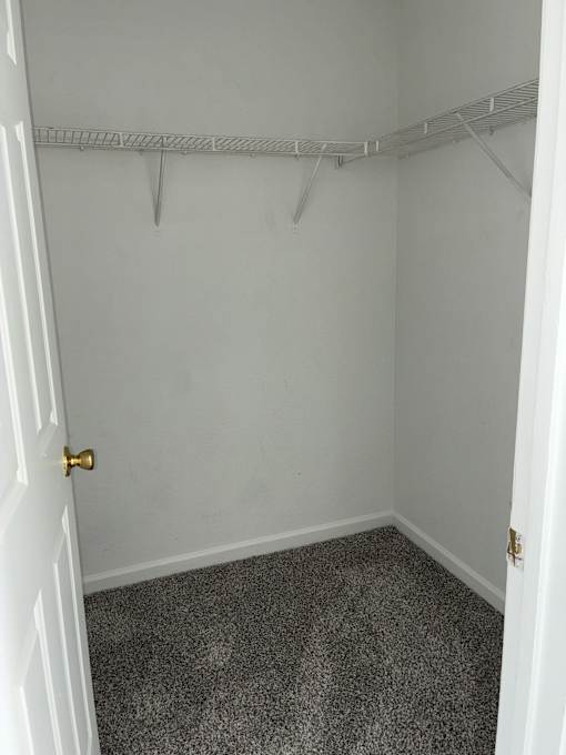 A white door is open to a small room with a metal rack on the wall.