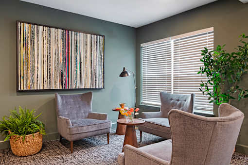 A living room with a grey chair, a brown chair, a small table, and a potted plant.