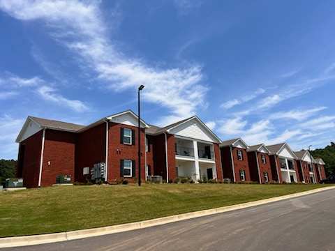 A row of red brick houses with white trim and green lawns.