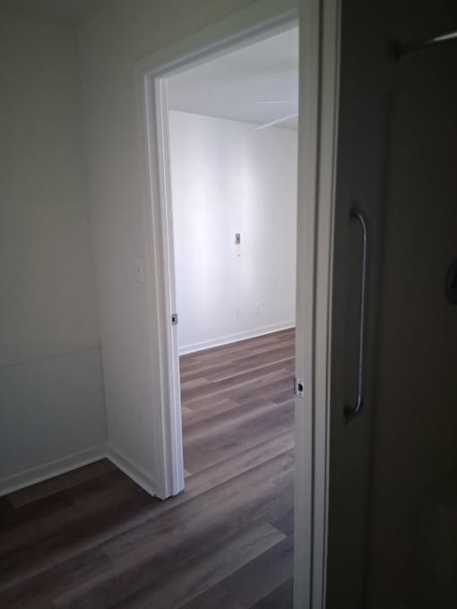 A white door is open to a room with wooden floors.