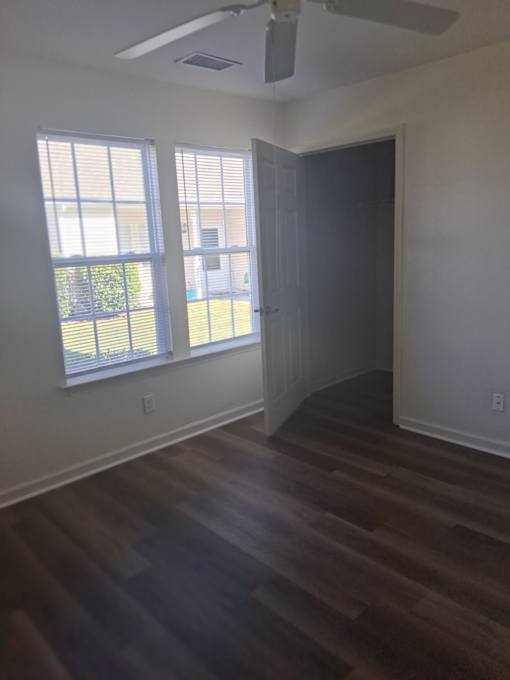 A room with a ceiling fan and a door leading to another room.