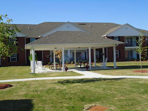 A large house with a covered patio and white furniture.