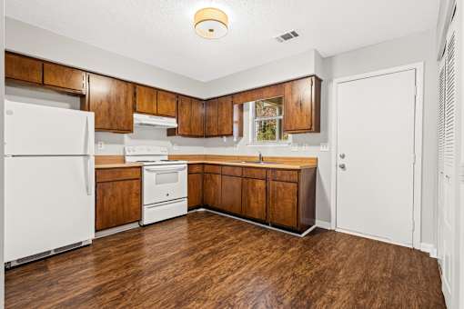 A kitchen with white appliances and wooden cabinets.