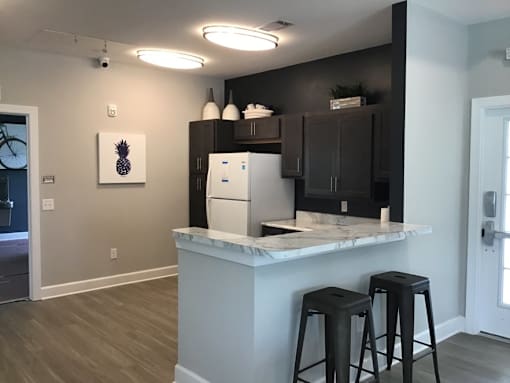 A kitchen with a white counter and bar stools.